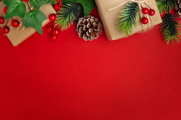 Gui, pommes de pin et cadeaux de Noël sur table rouge