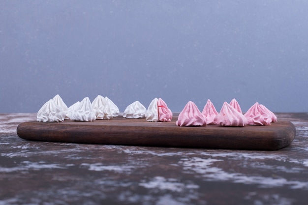 Photo gratuite guimauves en forme de fleur blanche et rose sur un plateau en bois bleu.