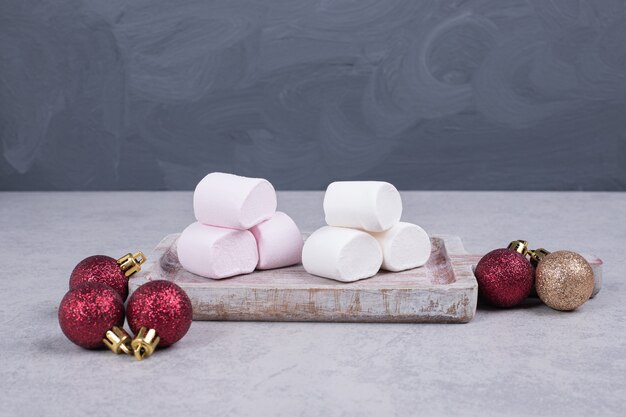 Guimauves sur planche de bois avec des boules de Noël. Photo de haute qualité