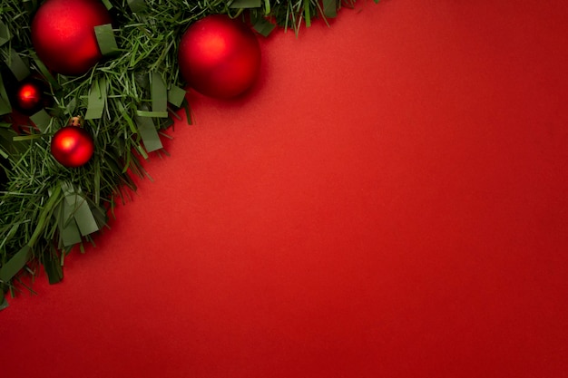 Guirlande de Noël faite de feuilles et de boules sur une table rouge