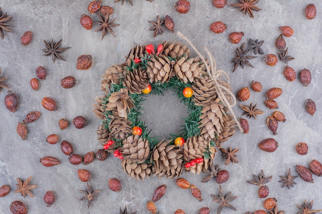 Guirlande de Noël avec pommes de pin et anis étoilé sur fond de marbre.