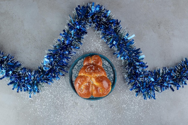 Guirlandes bleues en zig-zag à côté d'un petit pain sucré sur une table en marbre.