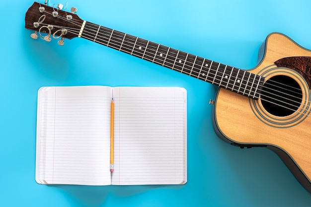 Guitare acoustique et bloc-notes sur une vue de dessus de fond bleu