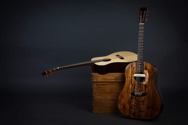 Guitare acoustique sur une chaise et guitare brune close-up dans le mur noir.