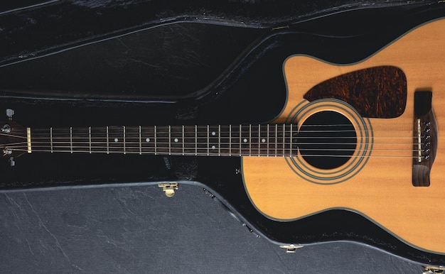 Guitare acoustique dans un boîtier de protection sur un fond sombre vue supérieure