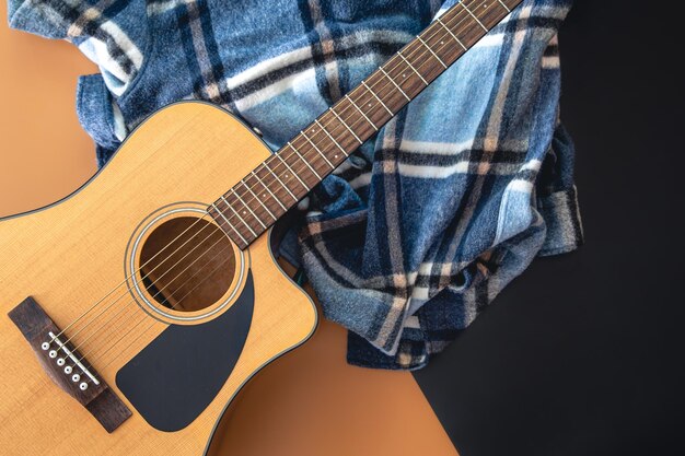 Guitare acoustique et plaid à carreaux sur une vue de dessus de fond coloré