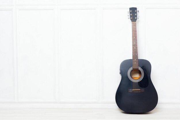 Guitare calée devant un mur blanc