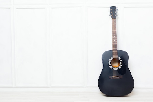 Guitare calée devant un mur blanc