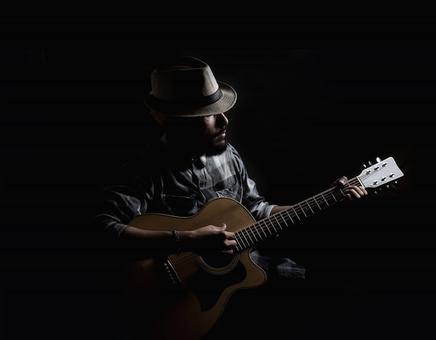 Le guitariste hipster jeune joue sur la guitare acoustique.