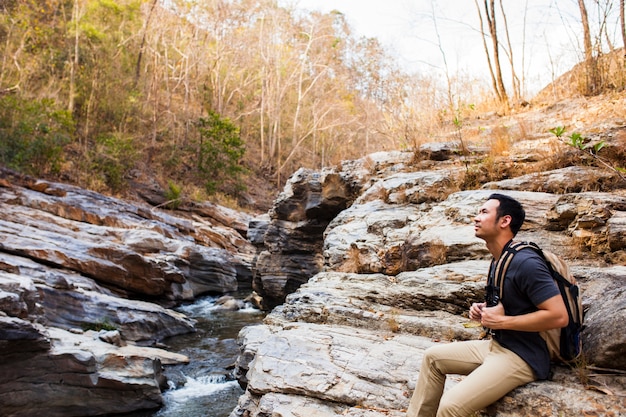 Guy assis sur des roches près de la rivière
