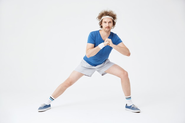 Guy en costume de sport rétro faisant des exercices d'étirement. blanc