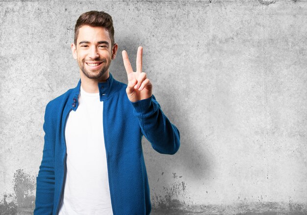 Guy dans une veste bleue avec les doigts de la victoire