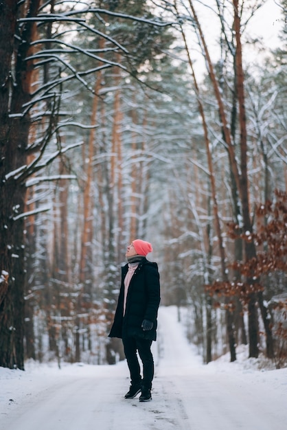 Guy debout sur la route au milieu de la forêt entourée de neige