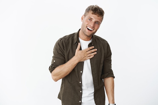 Photo gratuite guy faisant une promesse, étant honnête et parlant du cœur tenant la paume sur la poitrine, souriant largement avec un regard amical et digne de confiance