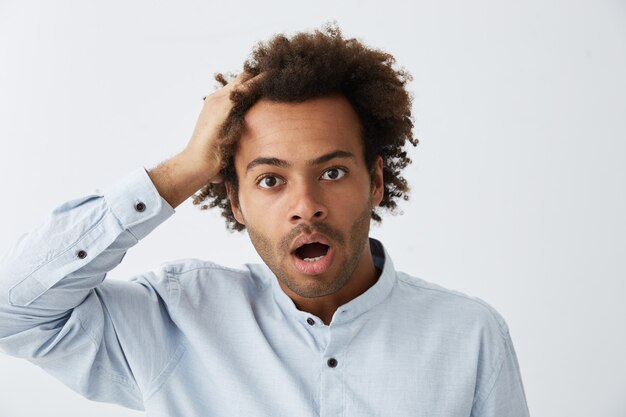 Guy hipster confus avec une coiffure africaine portant des vêtements formels