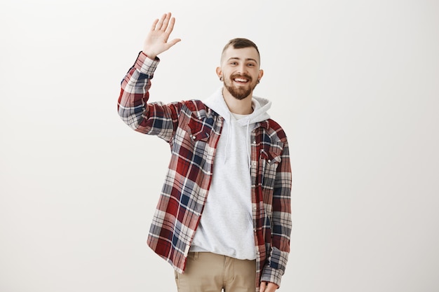 Photo gratuite guy hipster heureux amical agitant la main levée pour dire bonjour, vous saluer