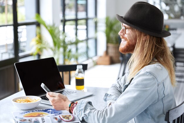 Guy hipster à la mode vêtu d'un chapeau noir élégant et d'une chemise en jean