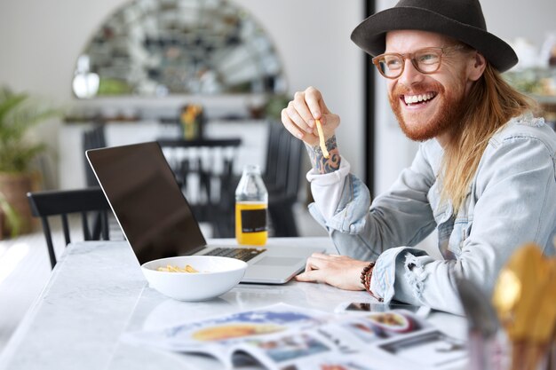 Guy hipster à la mode vêtu d'un chapeau noir élégant et d'une chemise en jean