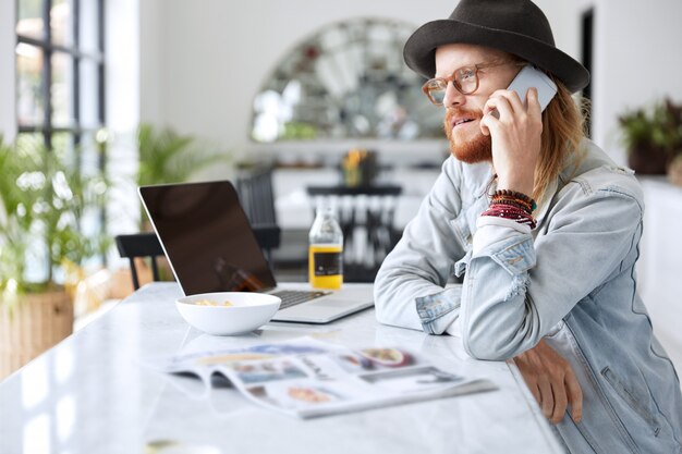 Guy hipster à la mode vêtu d'un chapeau noir élégant et d'une chemise en jean