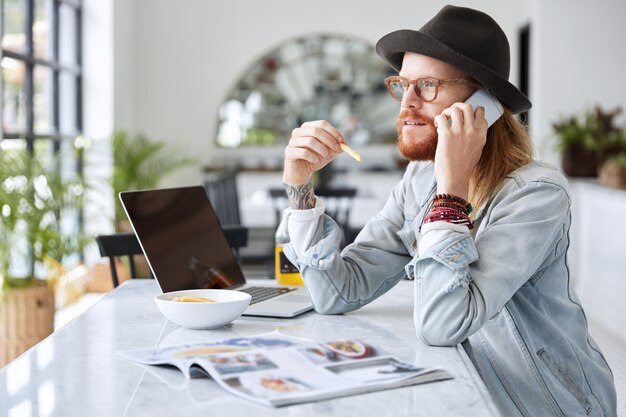 Guy hipster à la mode vêtu d'un chapeau noir élégant et d'une chemise en jean