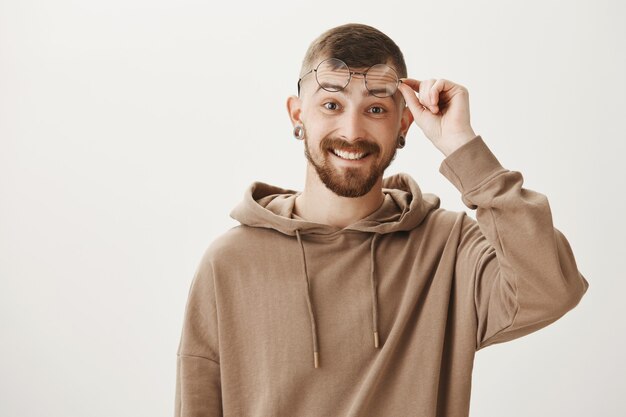 Guy hipster surpris avec barbe, souriant heureux et lunettes de décollage