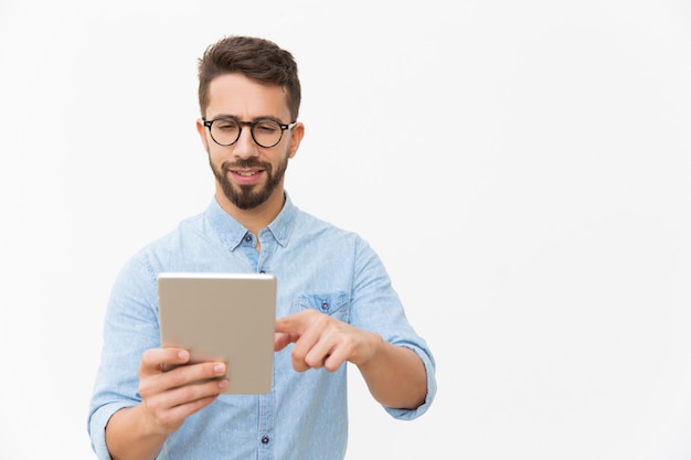 Guy positif concentré en regardant le contenu sur tablette