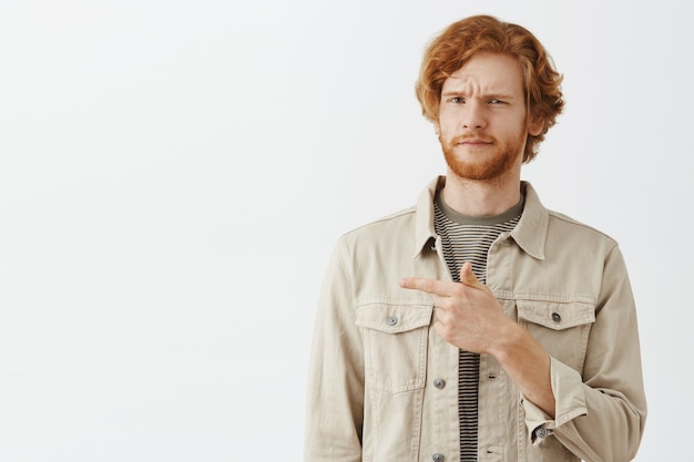 Photo gratuite guy rousse barbu confus posant contre le mur blanc