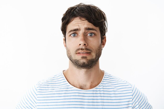 Guy se sentant mal à l'aise à l'air téméraire et désespéré à la vie tombant à part debout intense et triste levant les sourcils dans la tristesse d'être inquiet