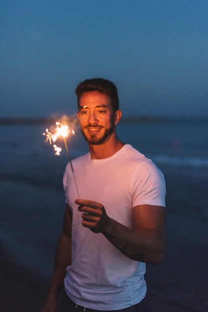 Guy avec un sparkler à la plage