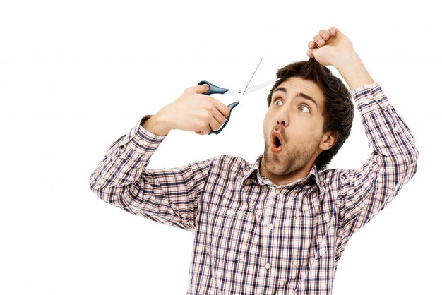 Guy tient des ciseaux, coupe les cheveux en auto-quarantaine