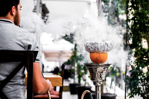 Guy vue de face fume la chicha avec une orange