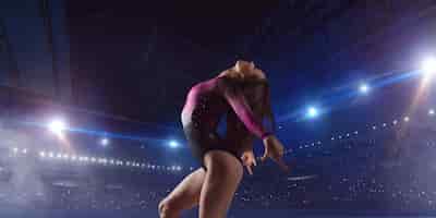 Photo gratuite gymnaste féminine faisant un tour compliqué sur la poutre d'équilibre de gymnastique dans une arène professionnelle