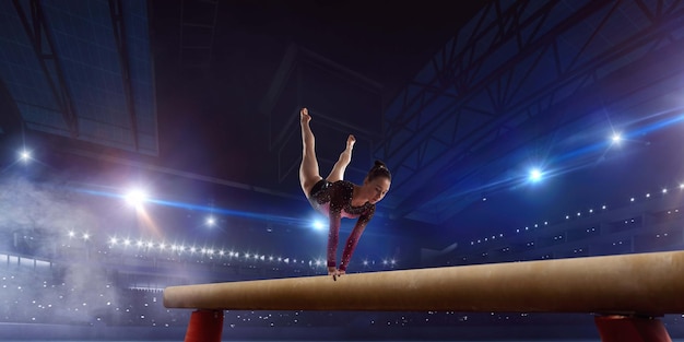 Gymnaste Féminine Faisant Un Tour Compliqué Sur La Poutre D'équilibre De Gymnastique Dans Une Arène Professionnelle