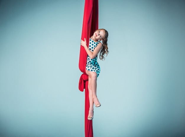 Gymnaste gracieuse assise avec des tissus rouges