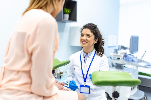 Gynécologue parlant avec une jeune patiente lors d'une consultation médicale dans une clinique moderne Patient avec un gynécologue lors d'une consultation au cabinet gynécologique