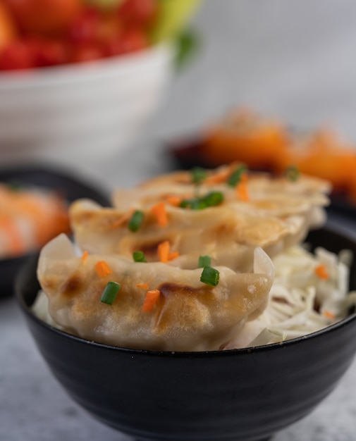 Photo gratuite gyoza dans une tasse noire avec sushi.