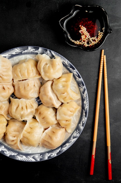 Photo gratuite gyoza avec sauce soja et baguettes sur une plaque