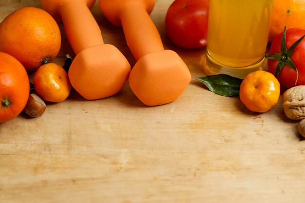 Haltère, jus d&#39;orange, fruits et noix sur la table en bois, mode de vie sportif et de santé