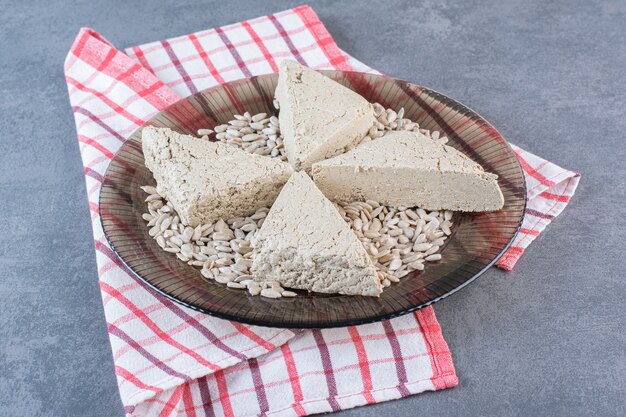 Halva de tournesol en tranches avec graines pelées sur la plaque de verre sur un torchon, sur la surface en marbre