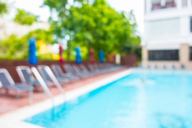 Hamacs avec des parapluies colorés dans une piscine floue