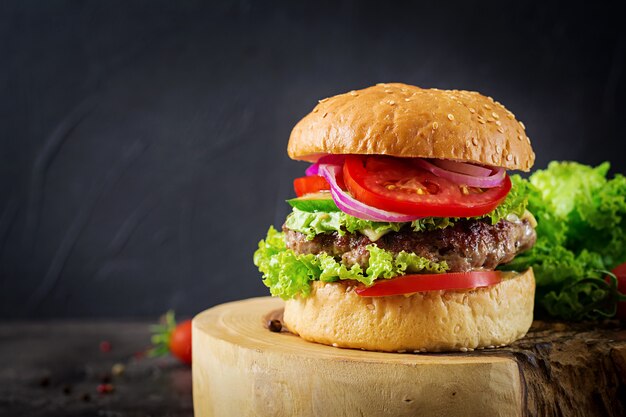 Hamburger avec hamburger de viande de boeuf et légumes frais sur table sombre. Nourriture savoureuse.