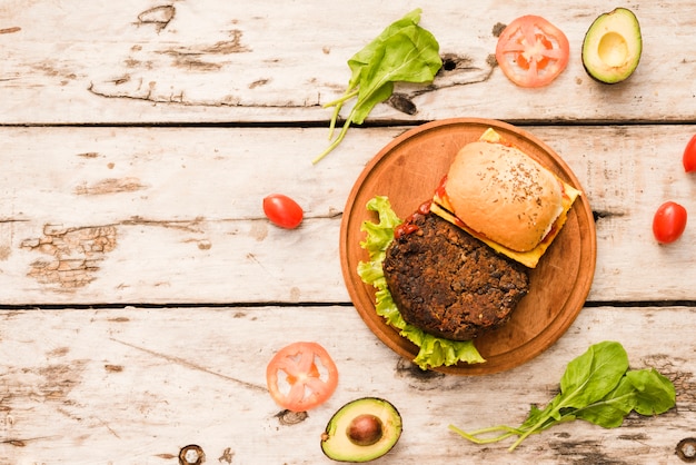 Hamburger sur une planche à découper avec des épinards; tomates; avocat sur planche de bois