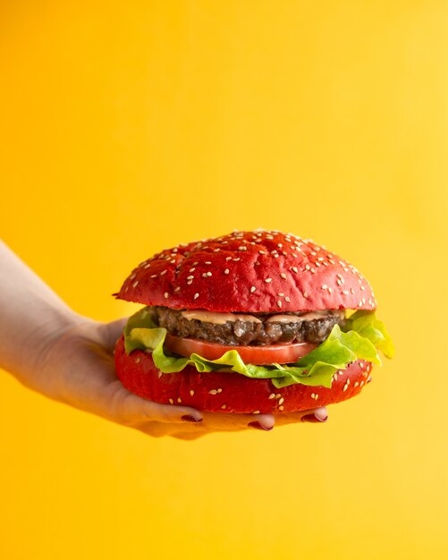 Hamburger rose une femme tenant un hamburger avec des feuilles de laitue tomate galette de boeuf et de la sauce dans des pains à hamburger