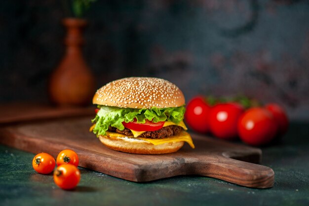 Hamburger de viande vue de face avec des tomates fraîches sur fond sombre