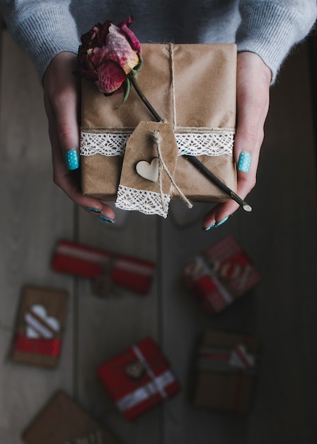 Photo gratuite hand holding package brun carré avec une fleur