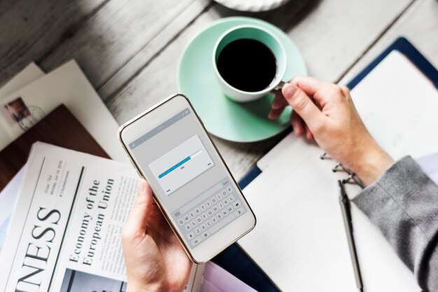 Hands Holding Downloading Mobile Phone avec une tasse de café