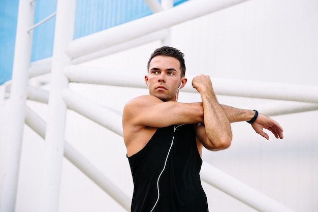 Hansome motivé sportif écoutant de la musique dans les écouteurs tout en faisant des exercices