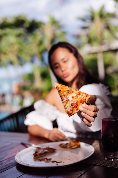 Happy Asian jolie femme faim ayant une pizza à la lumière du coucher du soleil journée ensoleillée dans le restaurant en plein air Femme appréciant la nourriture s'amuser au déjeuner