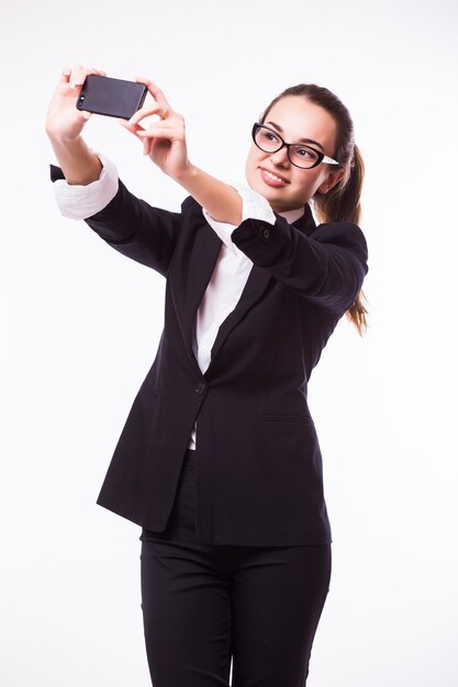 Happy businesswoman making selfie photo sur smartphone sur mur blanc