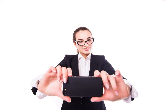 Happy businesswoman making selfie photo sur smartphone sur mur blanc